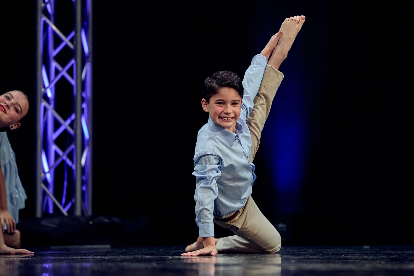 Young dancer kneeling mid-routine with a big smile