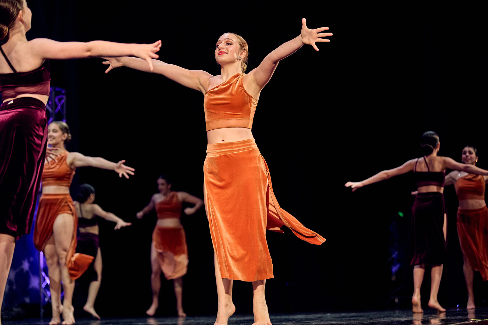 AFDS group routine in orange costumes, arms thrown wide