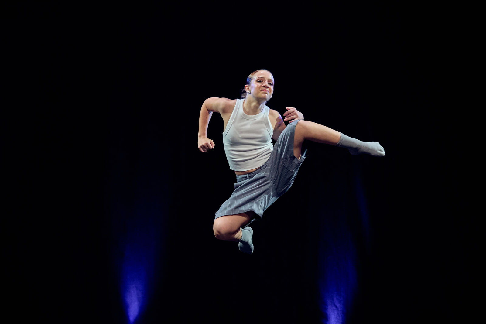 Contemporary dancer suspended mid-leap on a dark stage