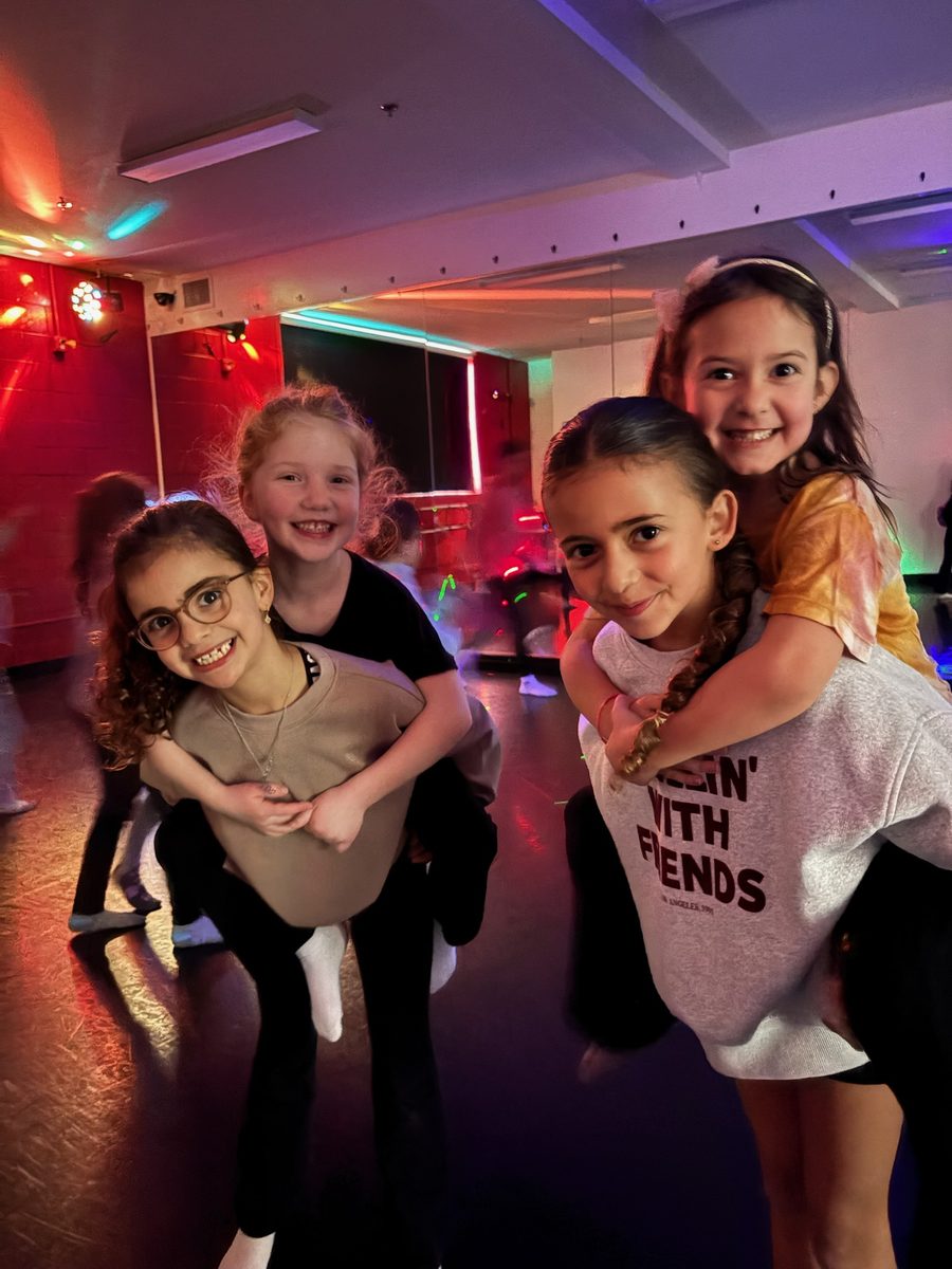 Three party guests grinning during a piggyback moment on the dance floor