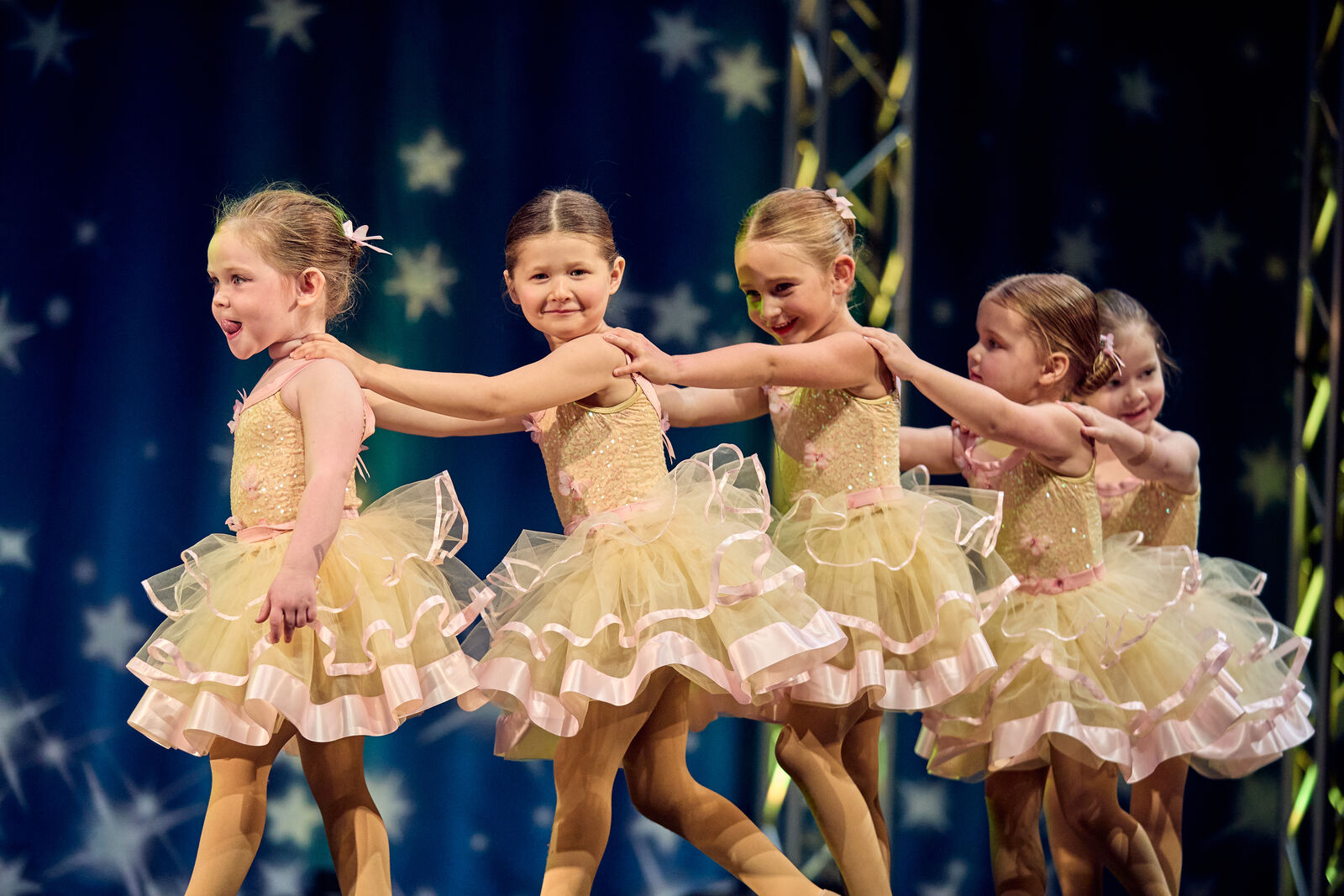 Four of our youngest dancers in yellow tutus lined up on stage